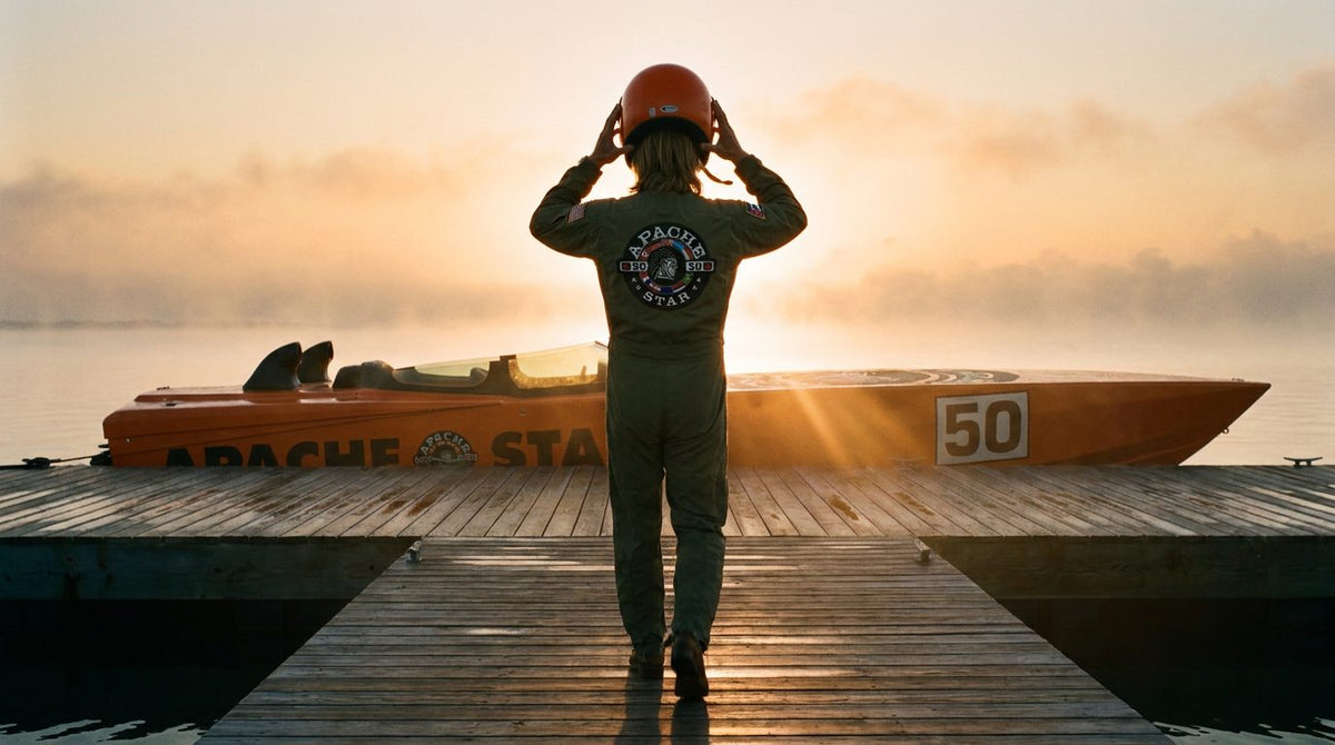 The rider walks along a wooden jetty toward the orange powerboat APACHE STAR at sunrise, putting on his helmet, in the film THE BRIDGE: 90 miles apart