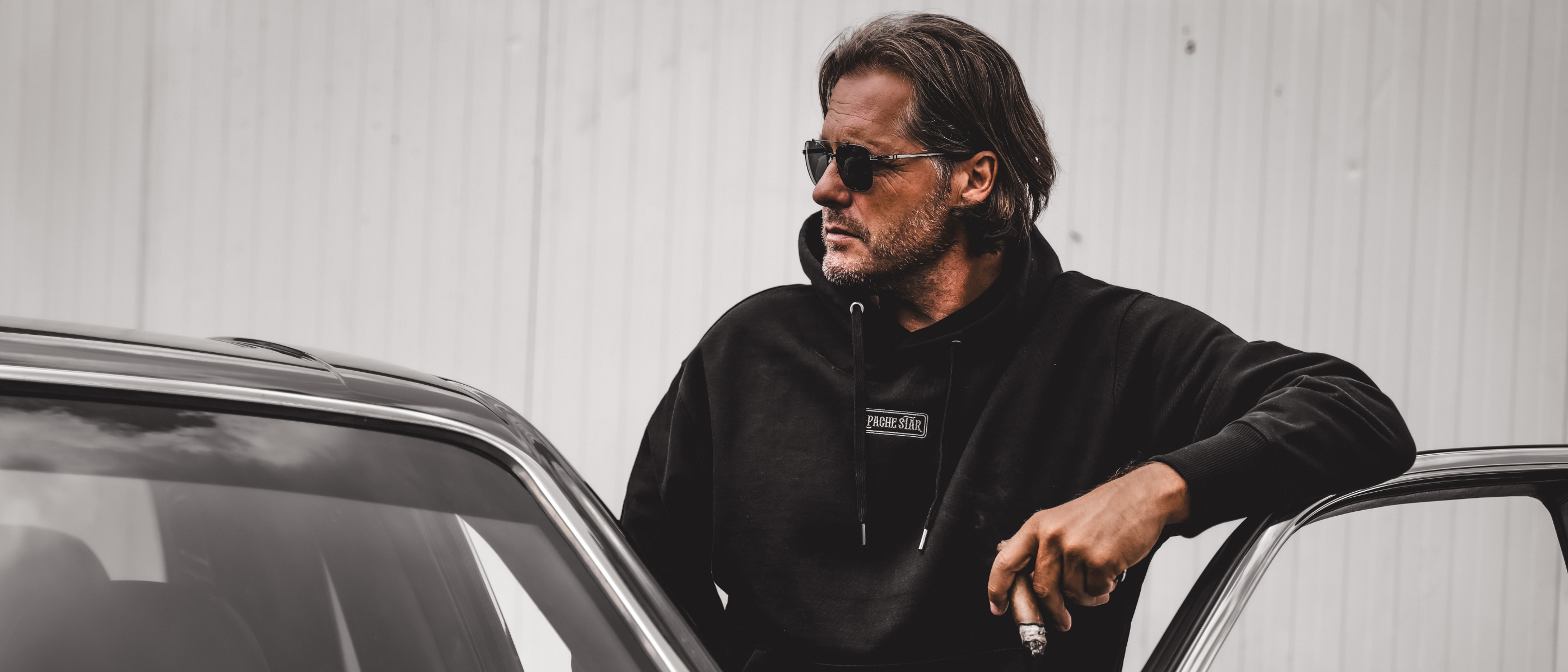 Roger Klüh in black APACHE STAR hoodie and sunglasses leaning on a black Bentley Arnage.
