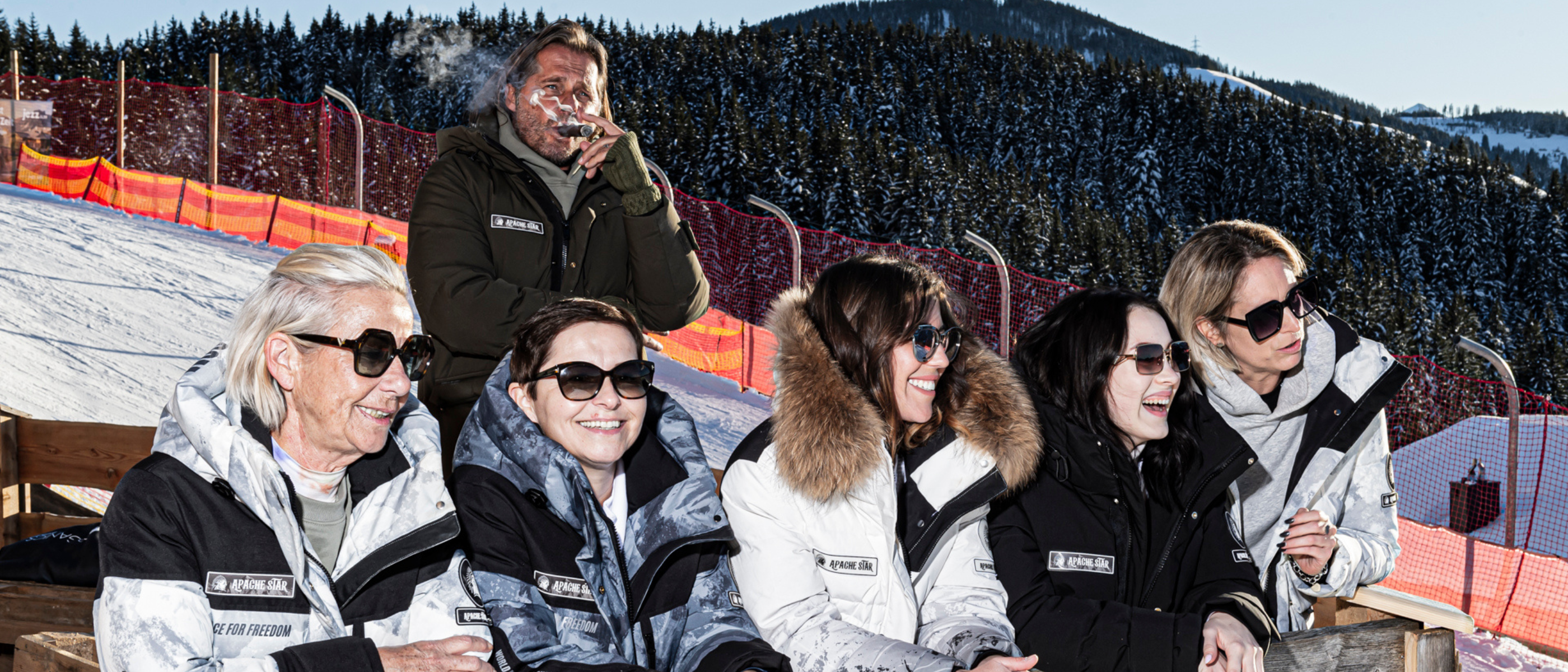 Stylish tech performance winter down jackets and coats by APACHE STAR worn by group in snowy mountain setting.