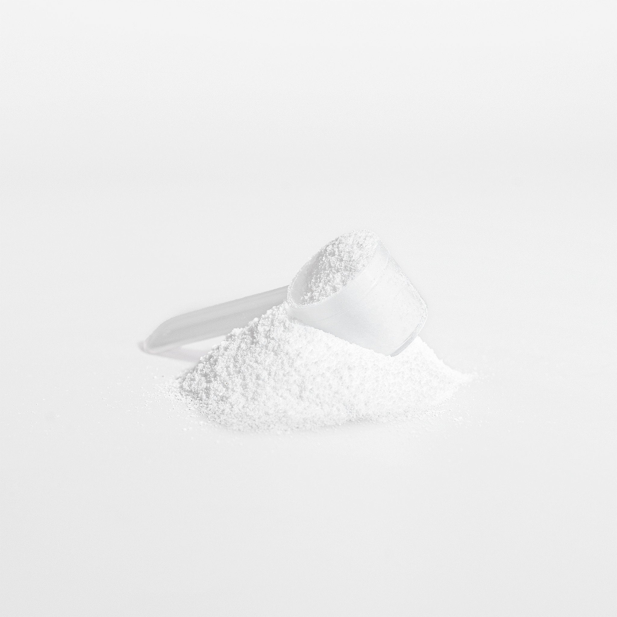 Close-up of pure white Creatine Monohydrate powder by APACHE STAR with a transparent scoop. Ideal for boosting energy and muscle mass in fitness routines.