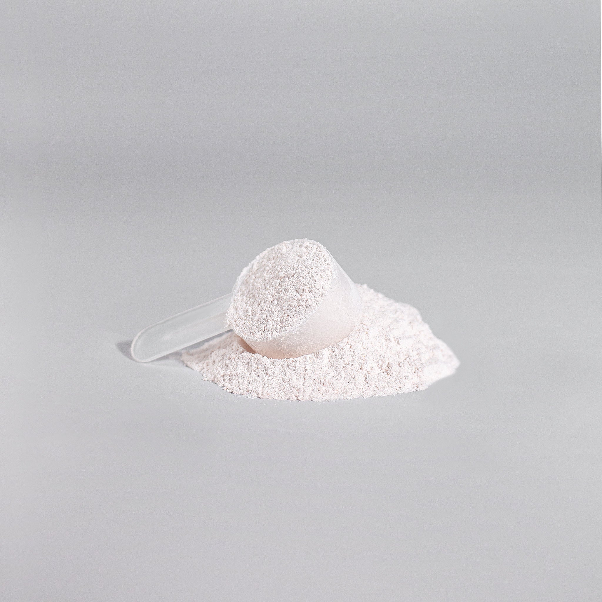 White scoop with powder on gray background for Nitric Shock pre-workout