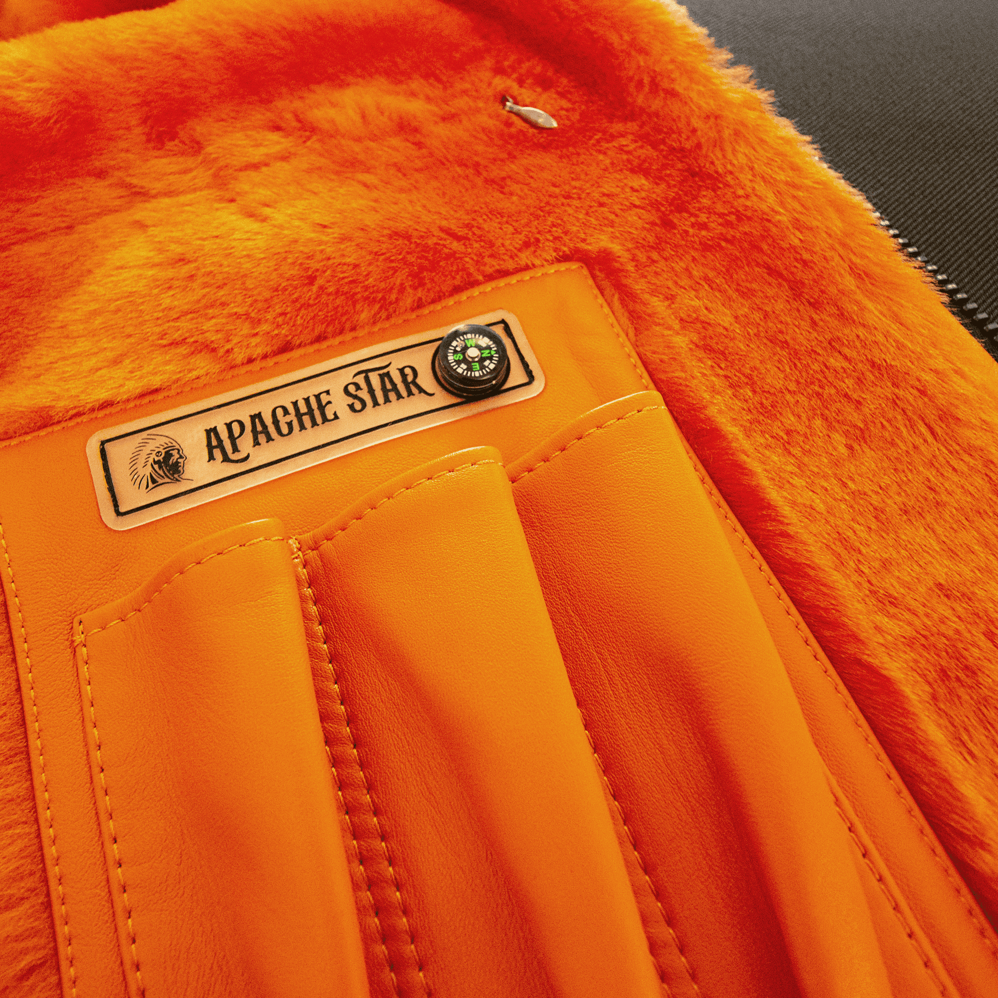 Interior detail of FLAMING AVIATOR by APACHE STAR Toscana Nappa Lamb Pilot Jacket with branded label and orange shearling lining. Luxury craftsmanship for fashion elites.
