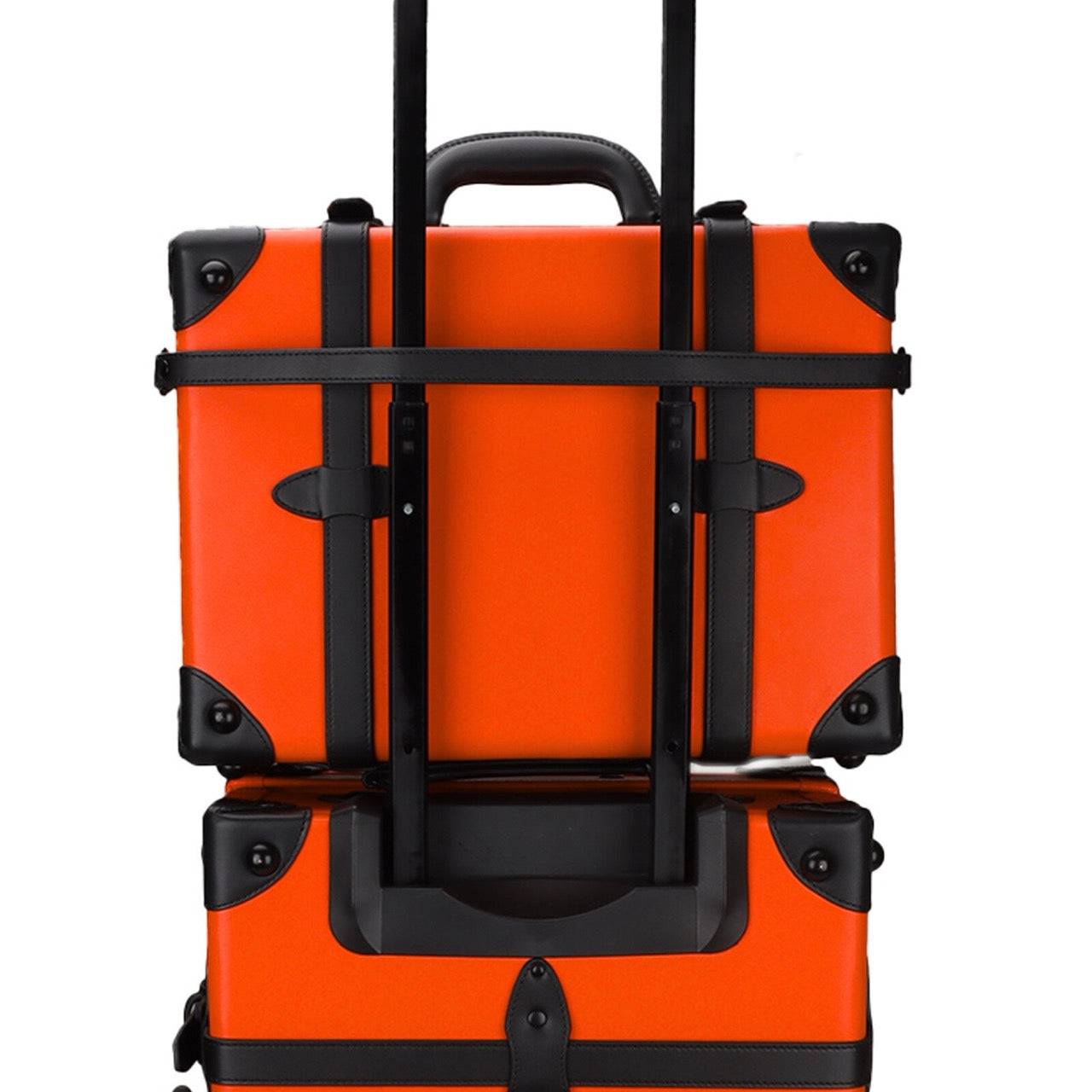 Back view of stacked APACHE STAR® Signature Orange suitcases showing telescopic handle and secure strap system for convenient transport.