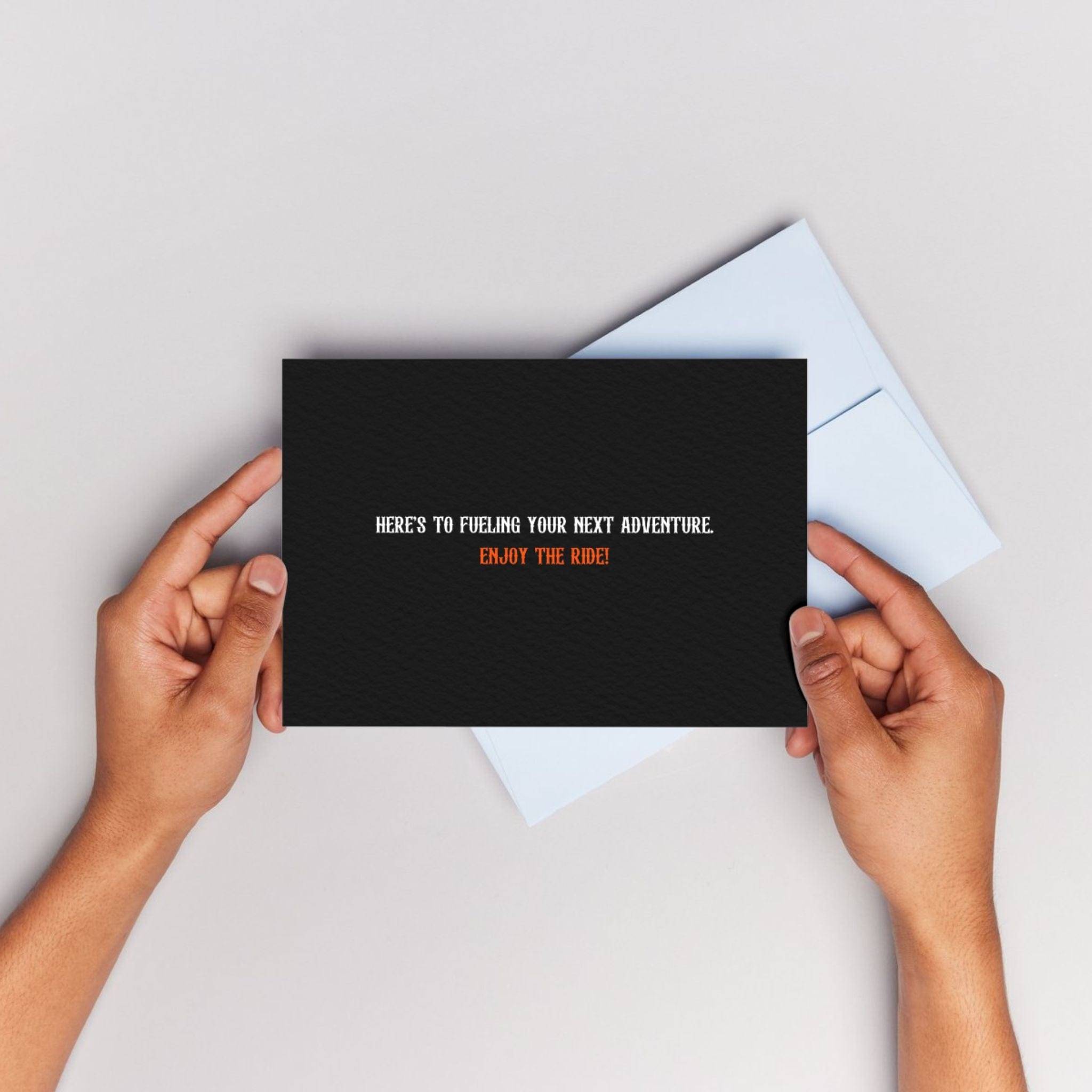 Gift Card - ENJOY THE RIDE by APACHE STAR held in hands with black front design and motivational message. Ideal for gifting fashion & supplements.