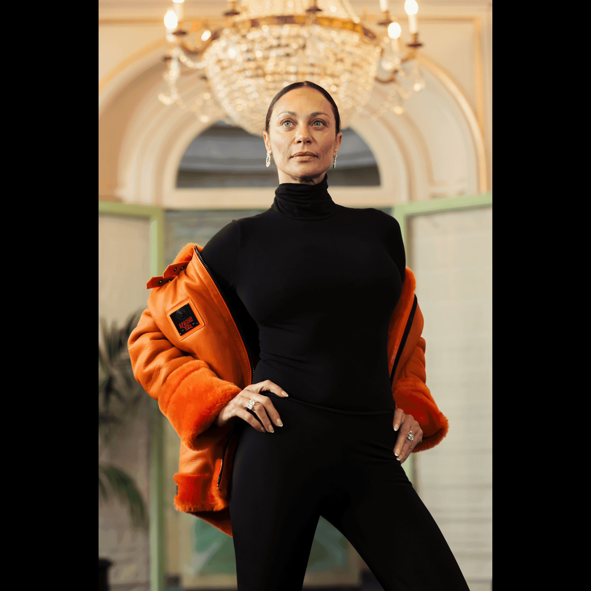 Close-up of Lilly Becker showcasing FLAMING AVIATOR by APACHE STAR Toscana Nappa Lamb Pilot Jacket with open front. Iconic orange Aviator jacket for stylish cigar connoisseurs.