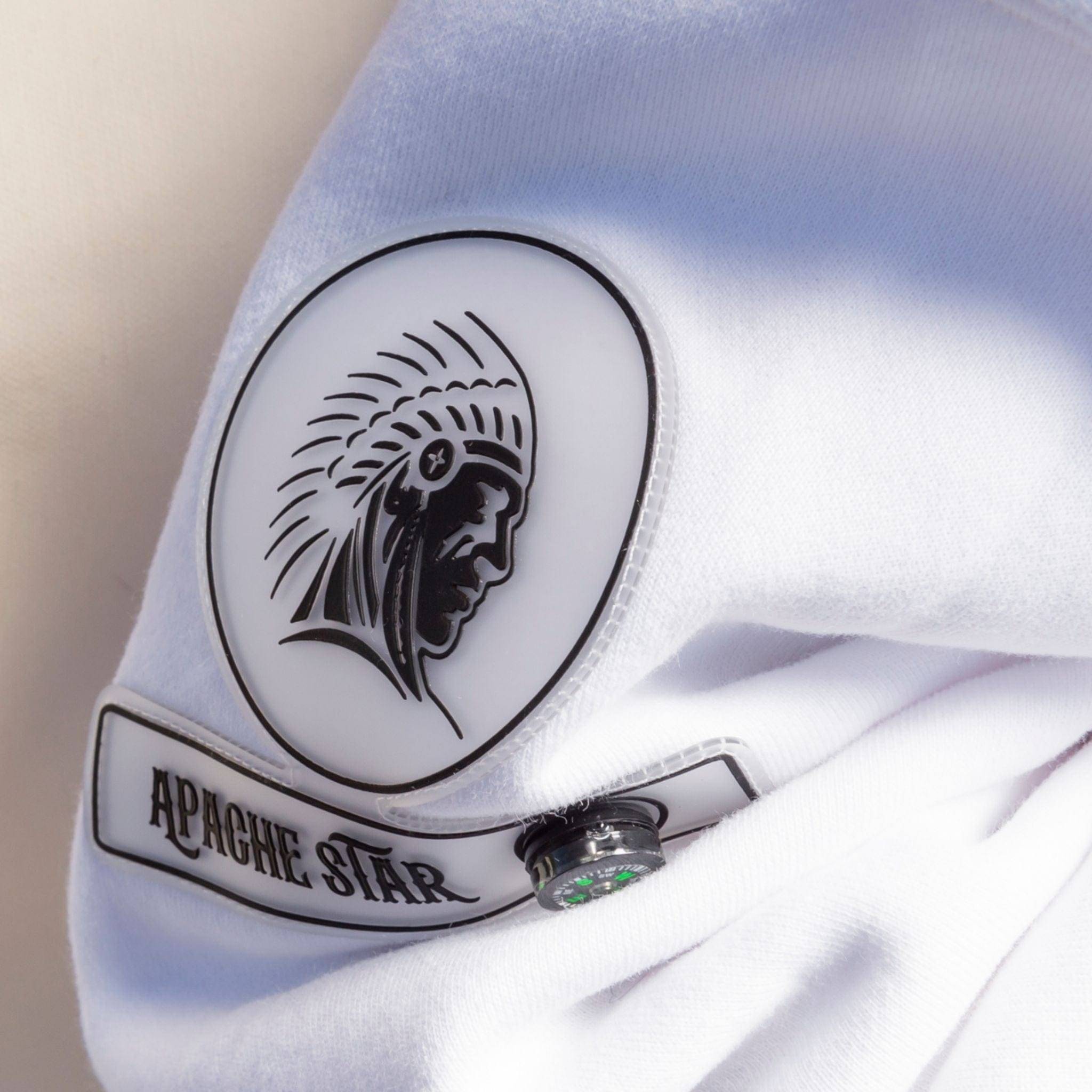 Close-up of white Iconic Dubai Hoodie by APACHE STAR sleeve, featuring detailed compass patch with tribal logo and brand name.