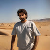BOXY TEE 'MANHATTAN' by APACHE STAR in beige worn by man in desert, showcasing breathable, quick-dry cotton ideal for summer adventures.