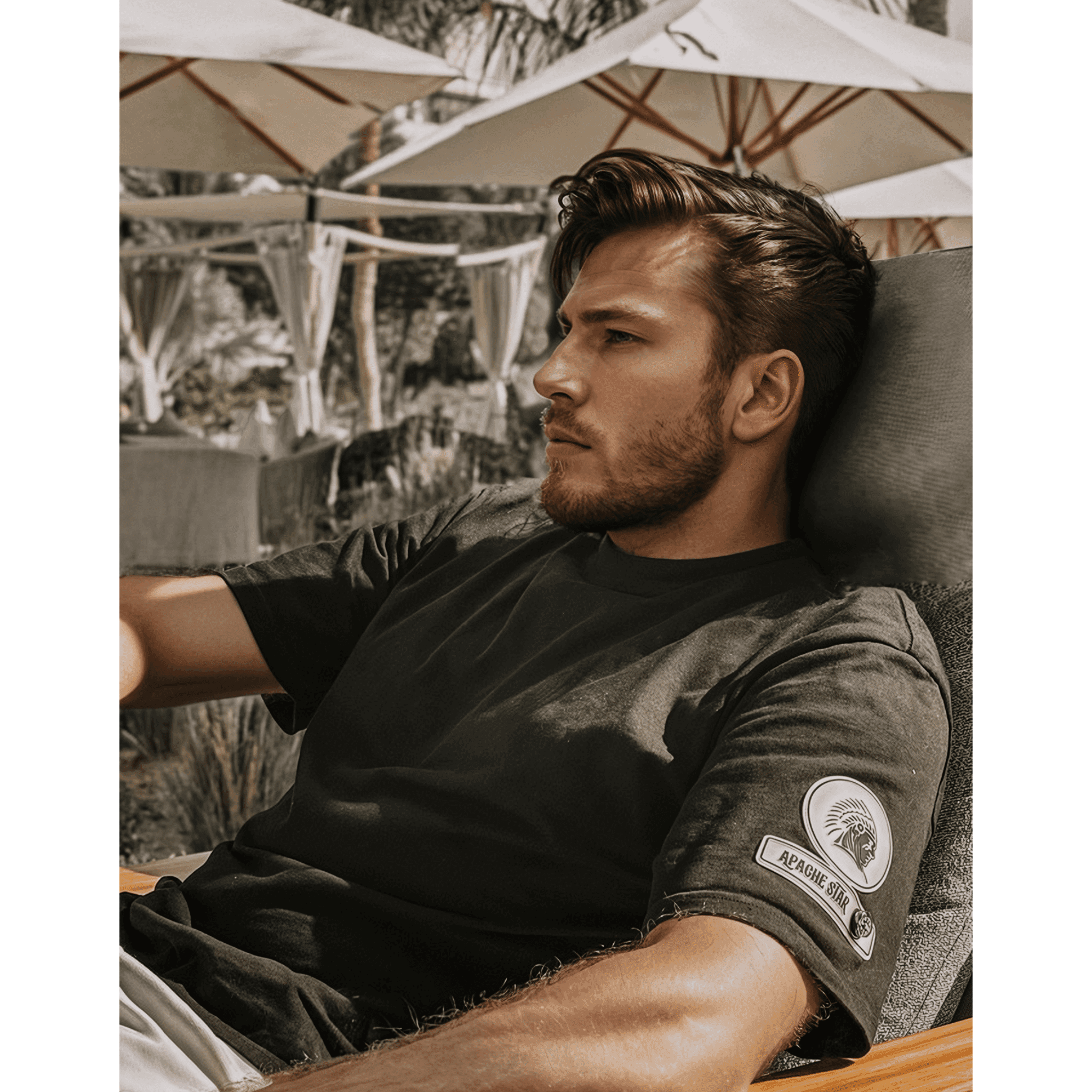 Man relaxing in black Iconic APACHE STAR Miami Tee, highlighting premium cotton comfort and stylish sleeve logo patch.