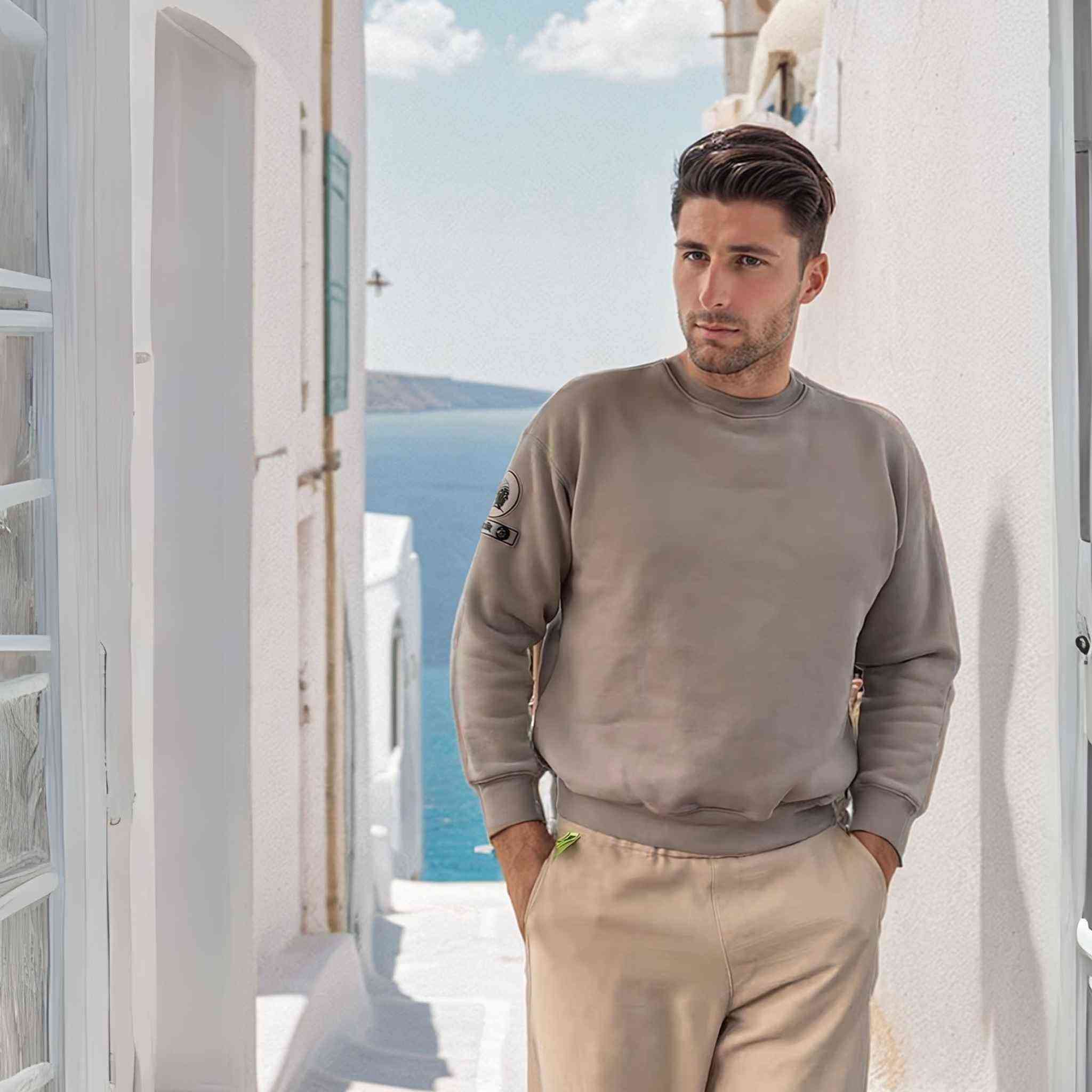 Monaco Sweatshirt in taupe by APACHE STAR, modeled by man in coastal alley. Organic cotton blend with signature compass patch.