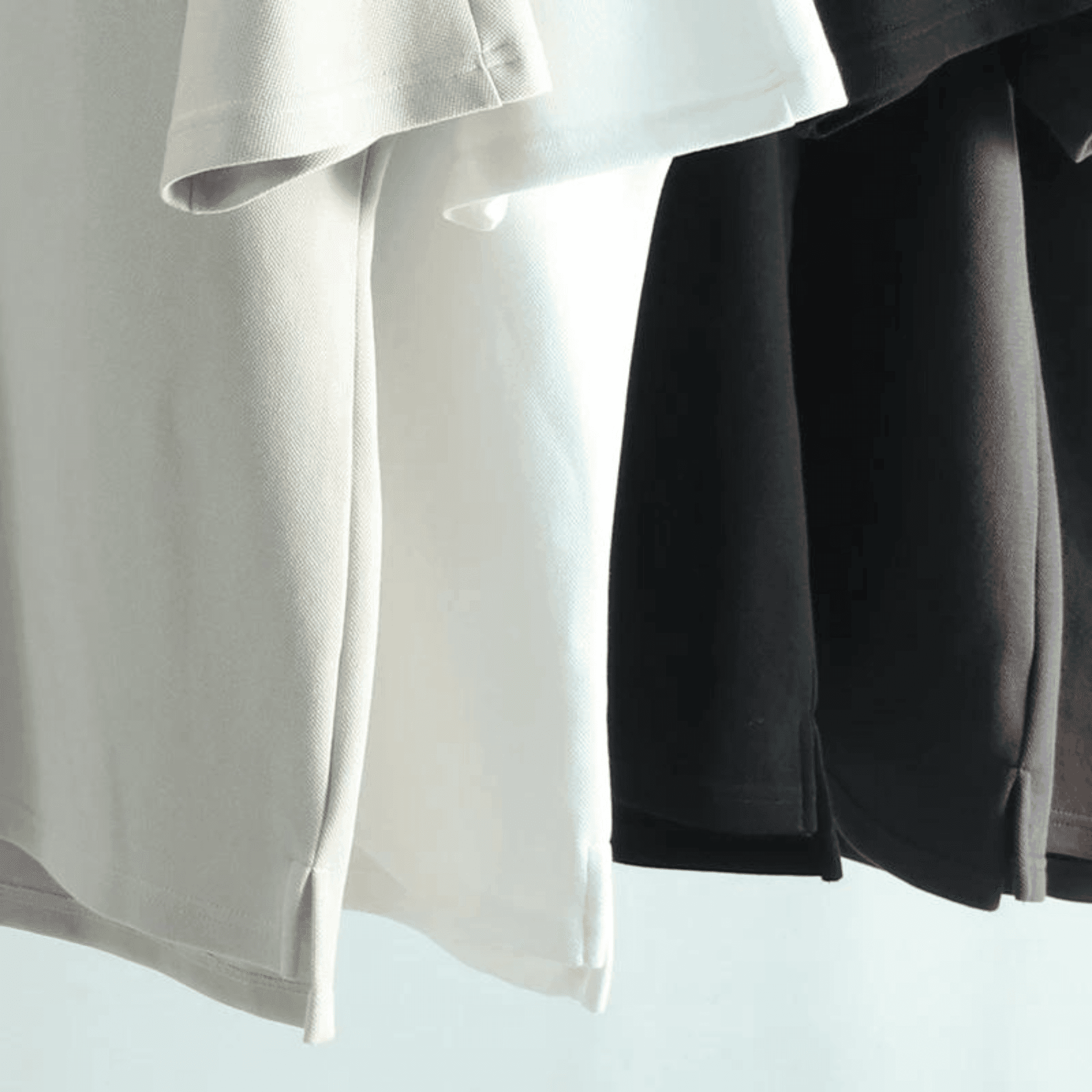 Close-up of BOXY TEE 'MANHATTAN' hems by APACHE STAR in white, black, and brown, showing side slits and premium cotton weave.