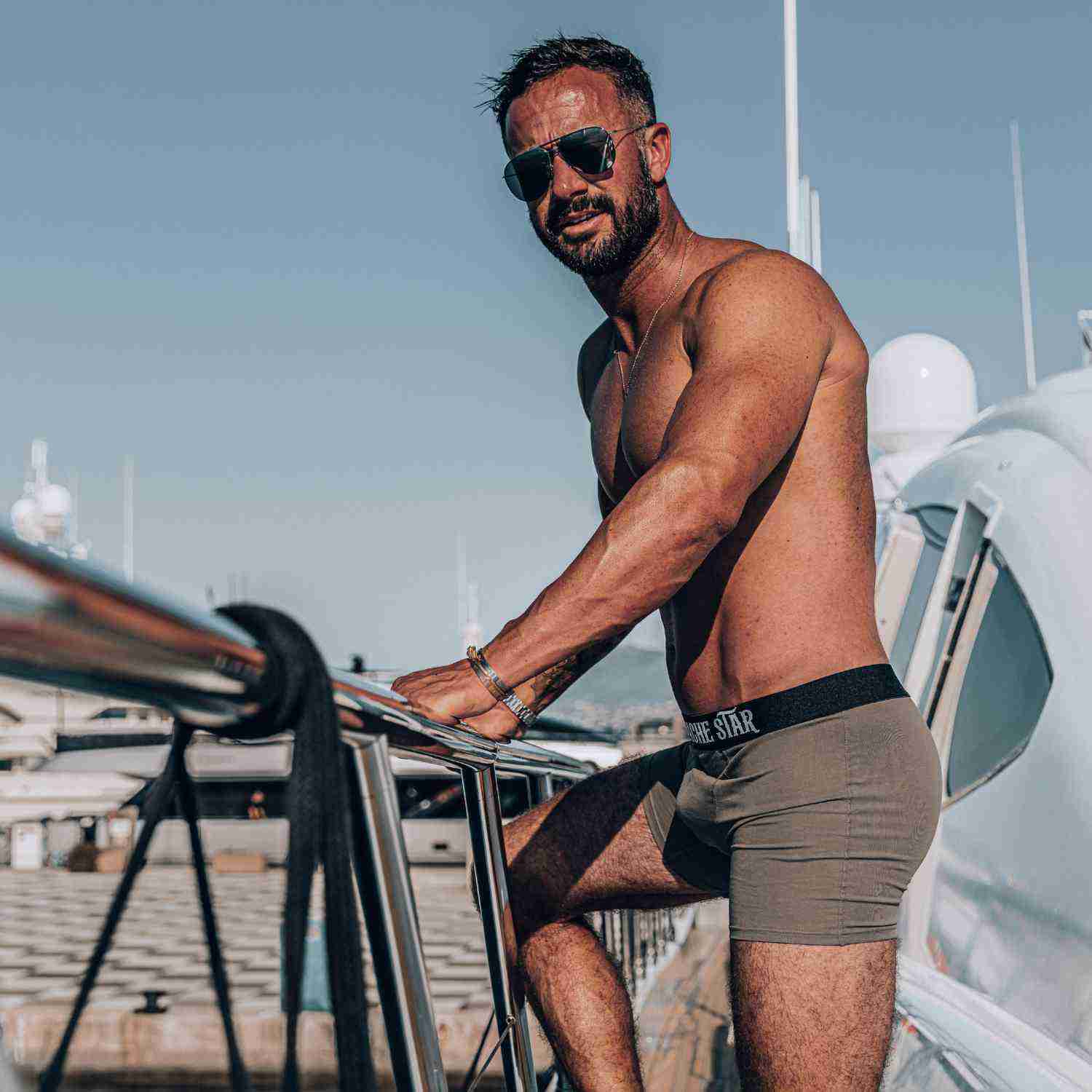 Man wearing sunglasses and boxer briefs on a yacht