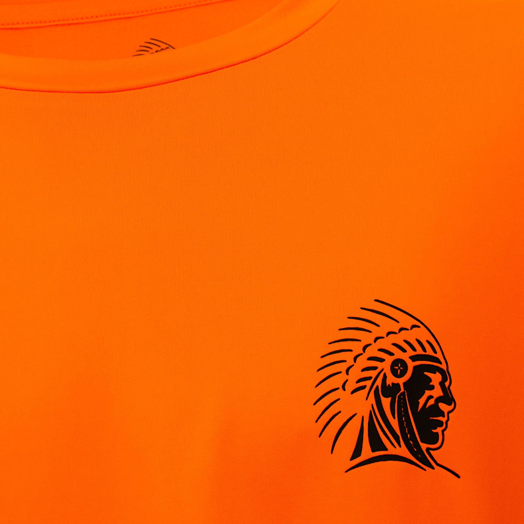 Close-up of the APACHE STAR Burning Battalion Shirt chest logo featuring a black tribal head graphic on high-performance orange fabric.