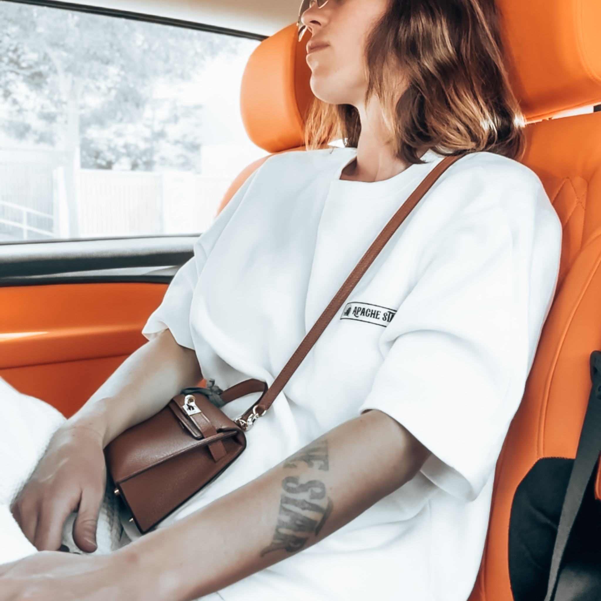 Jessica Frühbrodt wearing BOXY TEE 'MANHATTAN' in white while seated in car, highlighting relaxed fit and stylish comfort for travel.