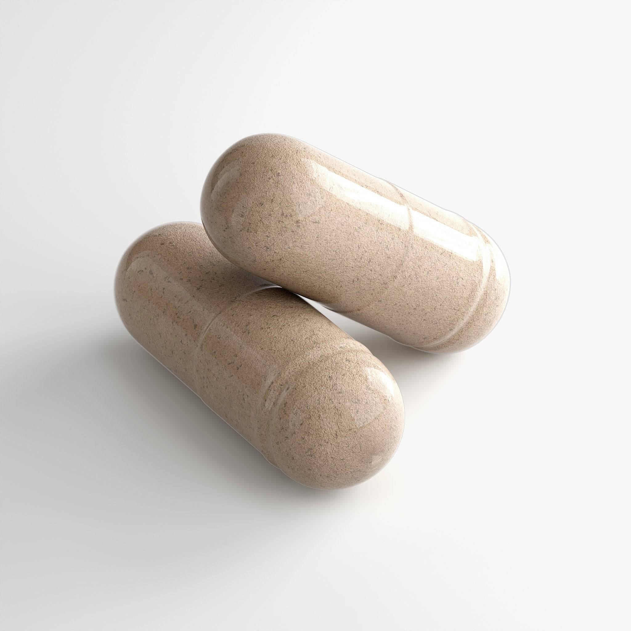 Close-up of beige capsules spilling from white supplement bottle