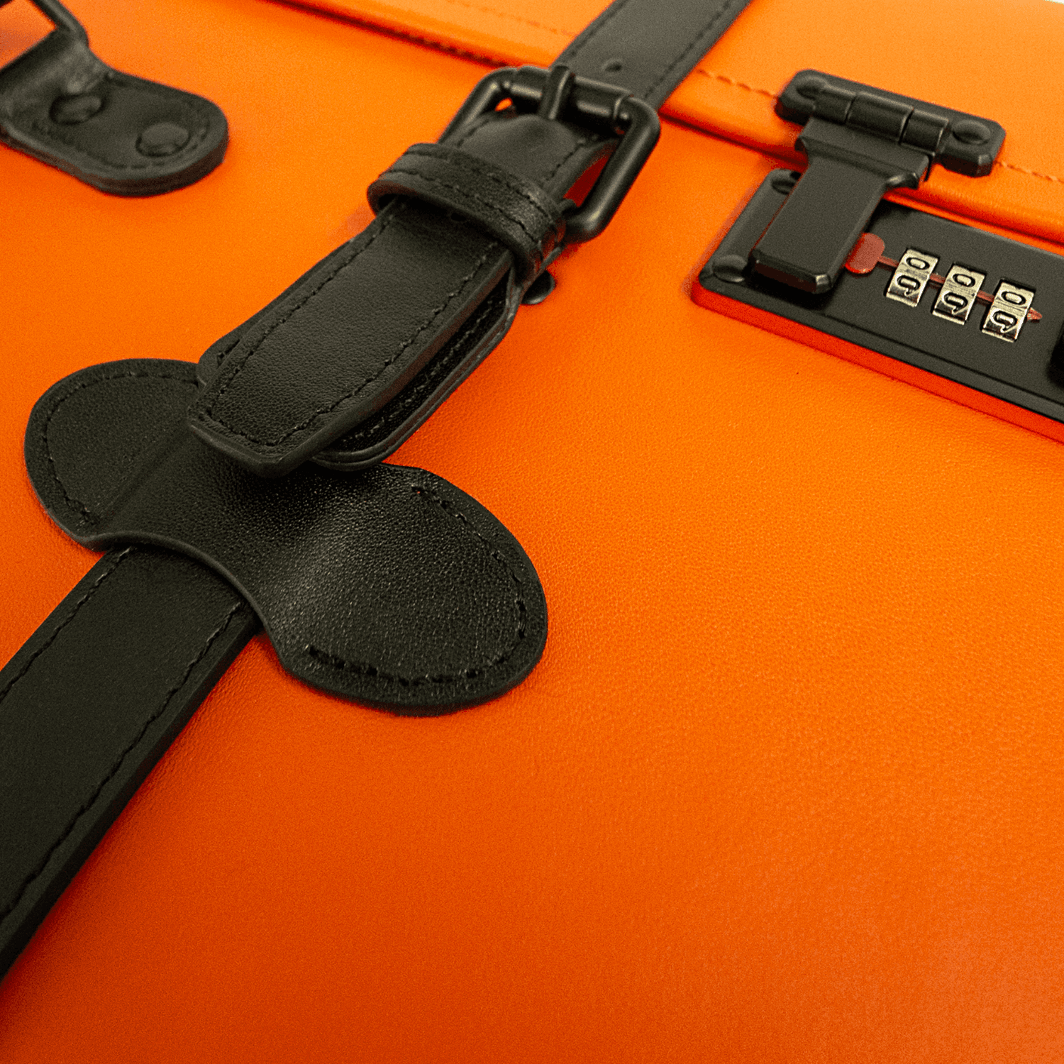 Macro shot of APACHE STAR® Signature Orange luggage showing black leather strap and TSA lock, highlighting premium craftsmanship and security.