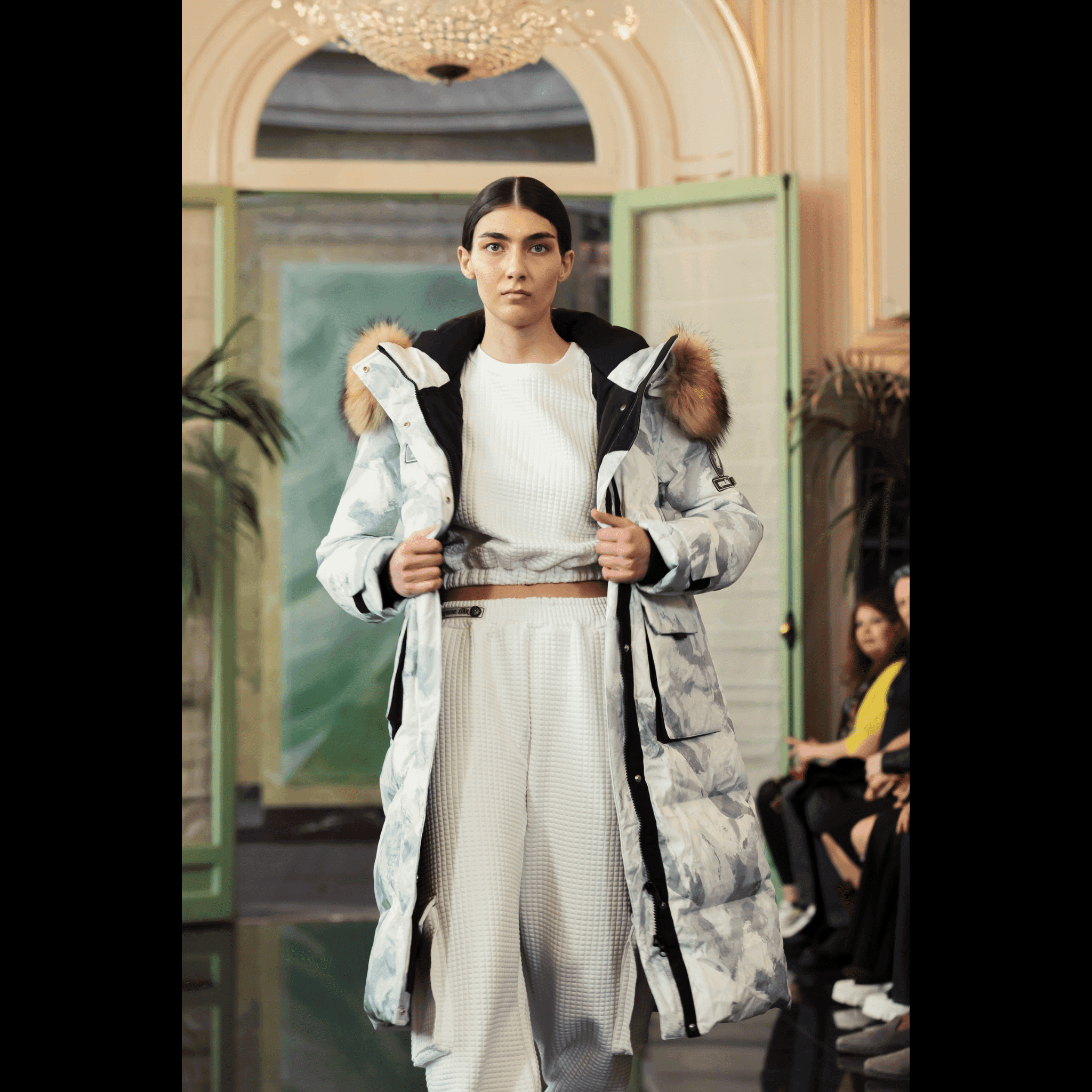 Runway model wearing Brigade Breeze Down Coat by APACHE STAR with fur hood, showcasing winter-ready fashion and functional outerwear at Paris Fashion Week.
