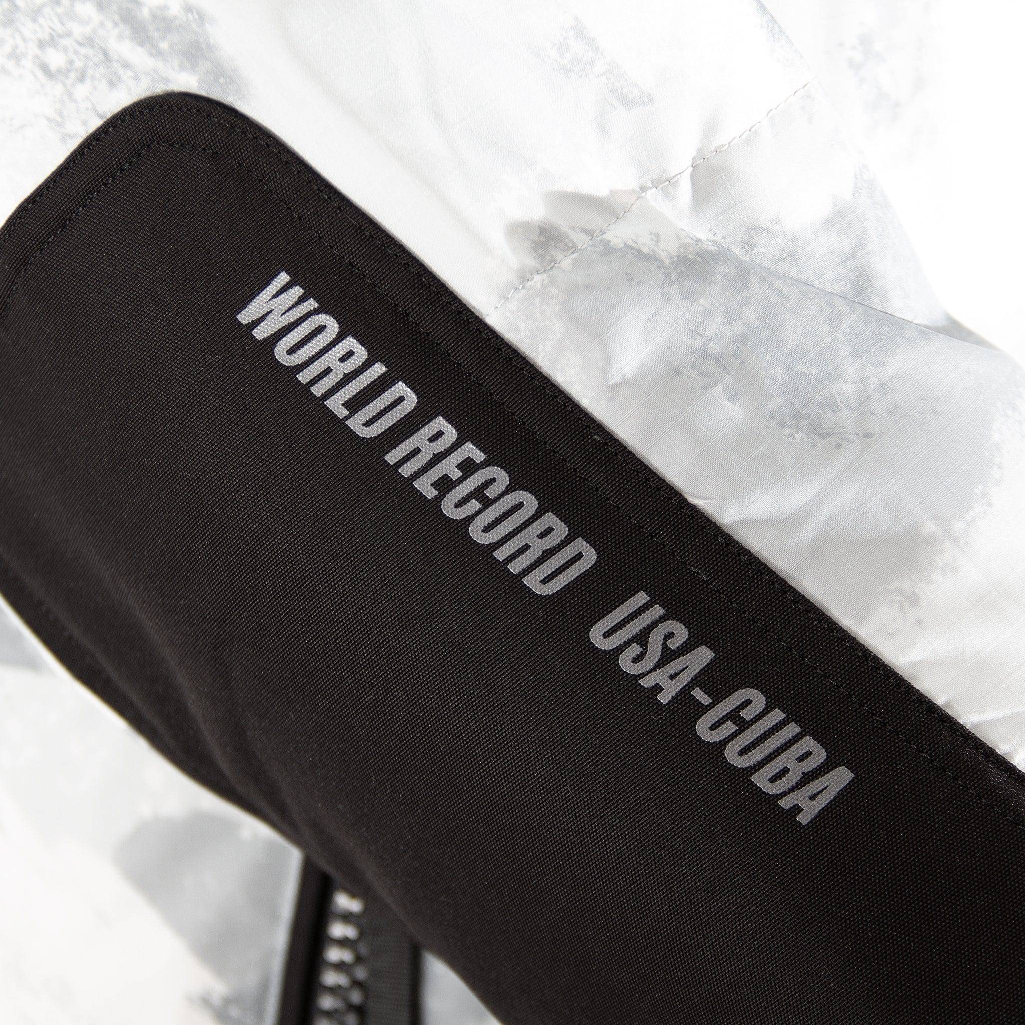 Detail of 'World Record USA-Cuba' text on sleeve of Submerged Sentry white down coat, showcasing unique storytelling and performance heritage.