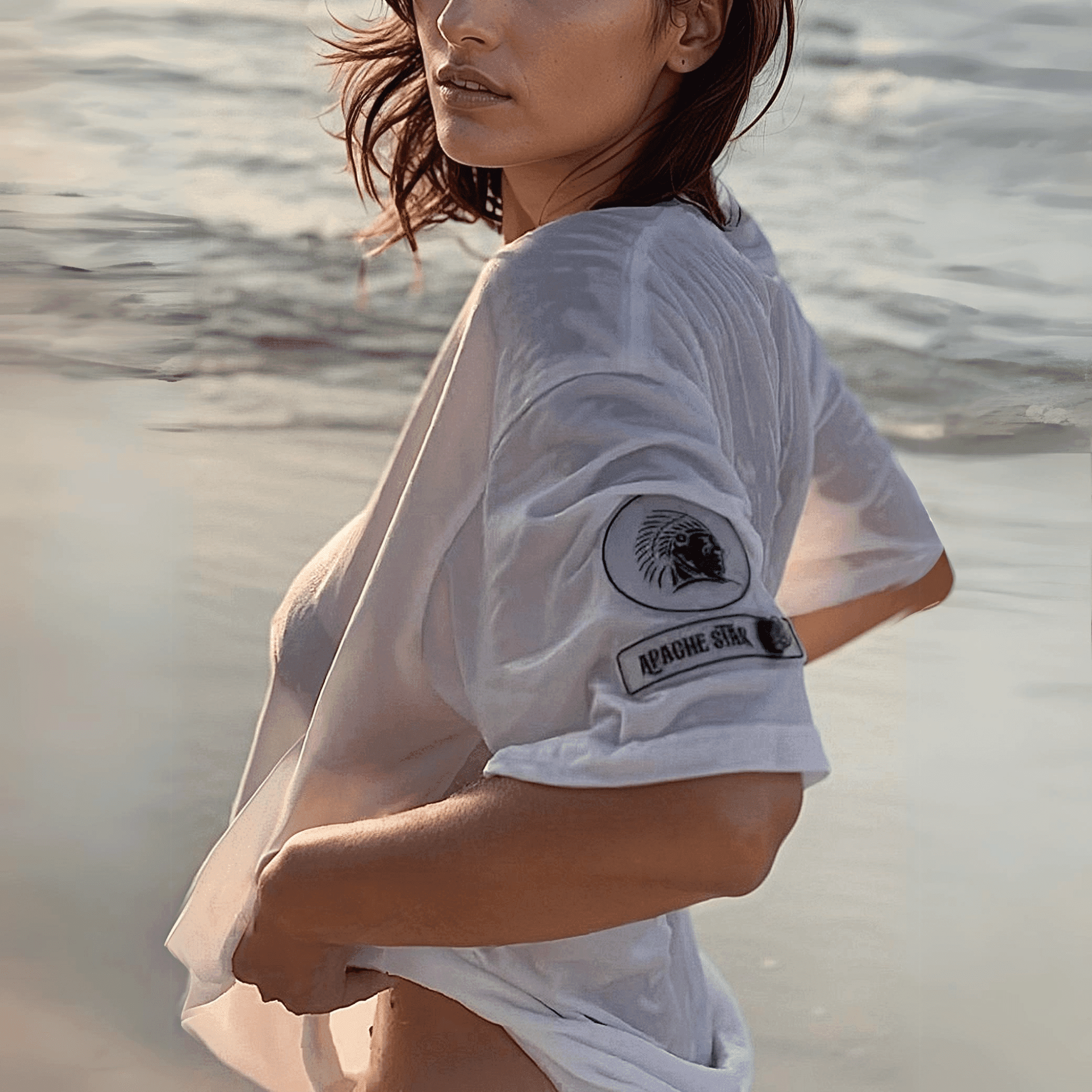 Woman wearing Iconic APACHE STAR Miami Tee in white on the beach, showcasing cooling technology and anti-wrinkle fabric for summer wear.
